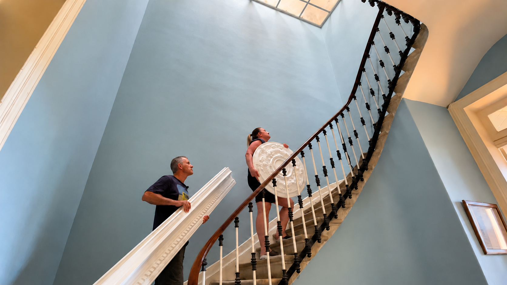 Deanne and Richard carrying a ceiling rose and decorative cornicing up the staircase at La Maison Lumière
